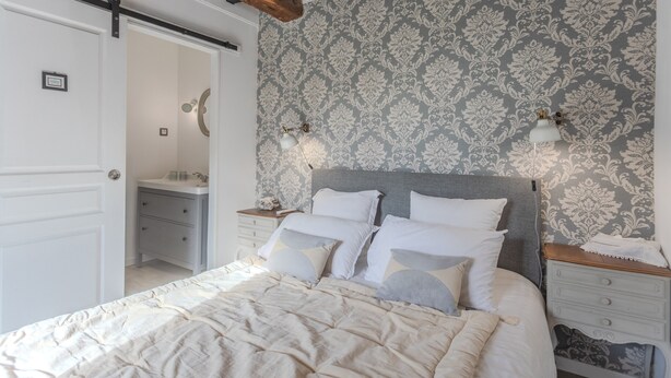 Un dormitorio con cama, mesitas de noche, un espejo y una puerta.