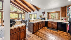 A spacious kitchen with wooden cabinets, a large island, and a view of the outdoors. - Evergreen Hideout Retreat (Kings Beach)