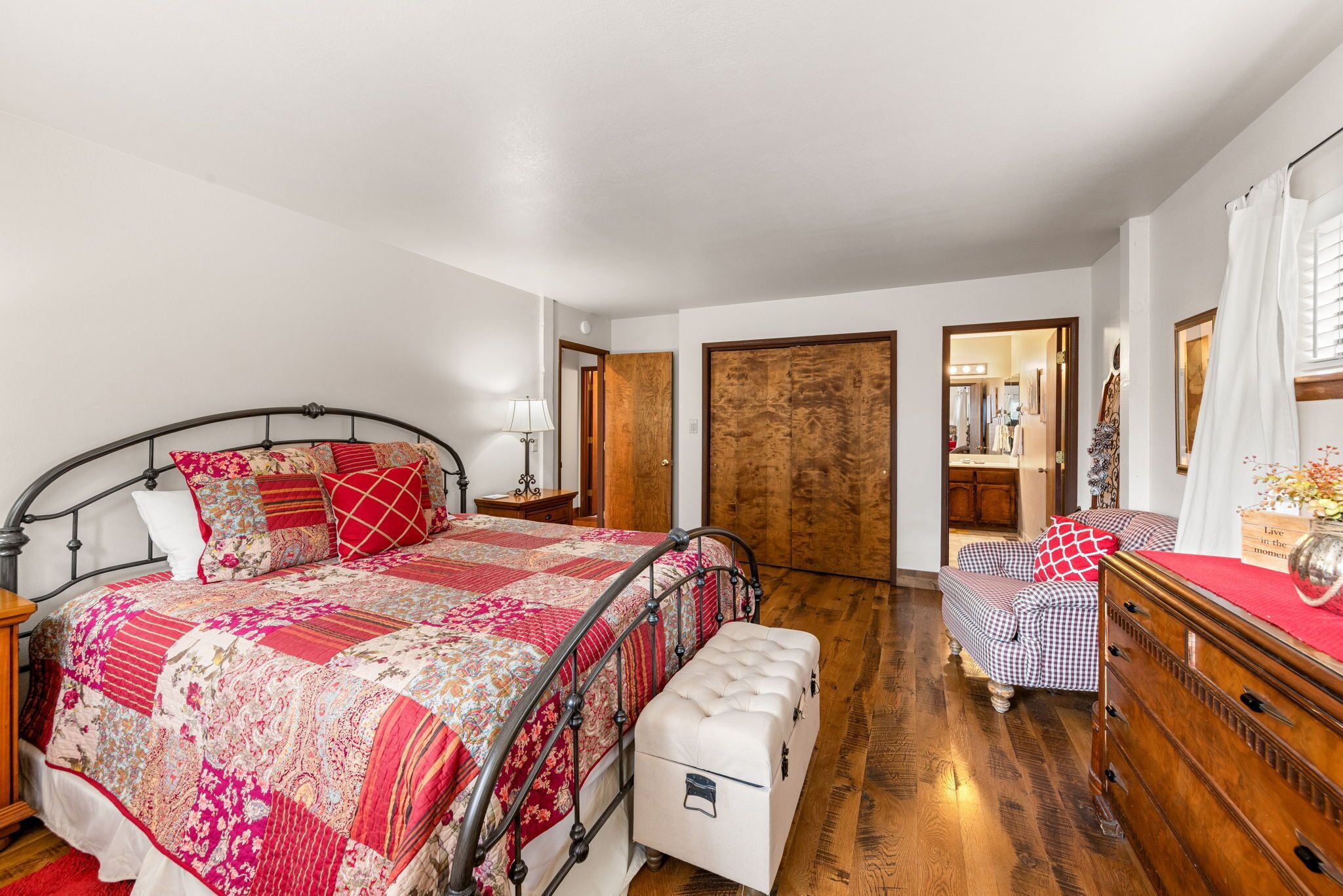 Een slaapkamer met een groot bed, een nachtkastje, een kaptafel en een spiegel.