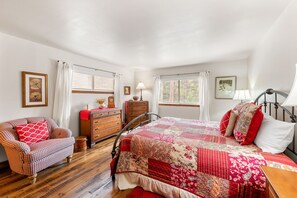 Un dormitorio con cama, una silla, cómoda y ventana.