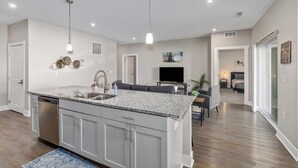 Une cuisine moderne dotée de plans de travail en granit, d’appareils électroménagers en acier inoxydable et de luminaires suspendus.