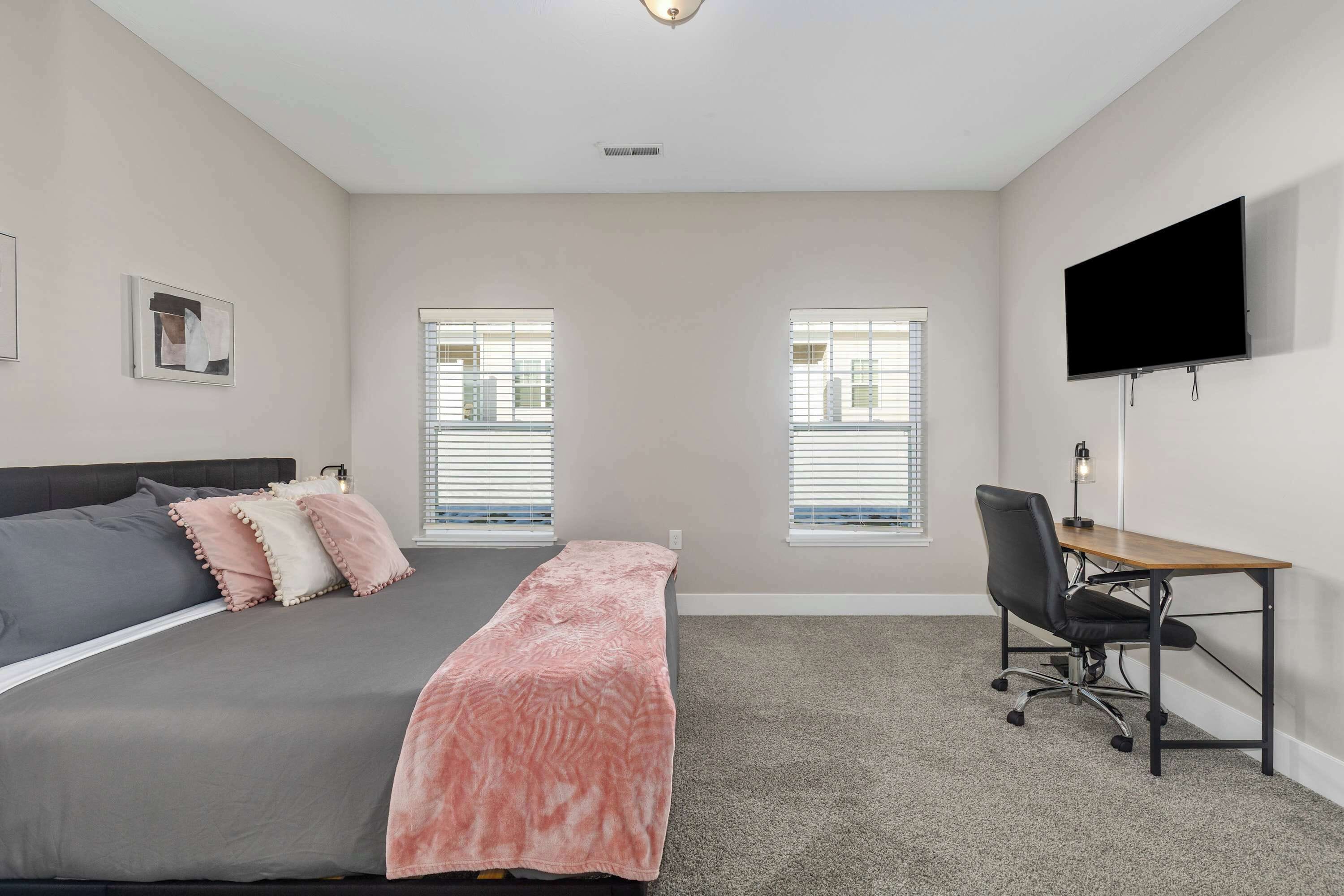 A bedroom with a bed, a desk, and a TV.