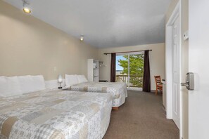 A hotel room with two beds, a balcony with a view, a desk, and a chair.