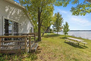 En hytte med terrasse og picnicbord ved en sø.