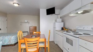 Eine kompakte Küche mit Herd, Mikrowelle und einem an der Wand befestigten Flachbildfernseher.