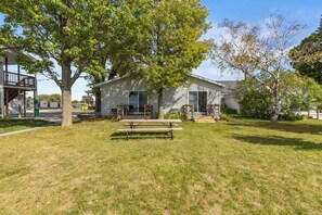 A single-story building with a covered porch and a picnic table in the front yard.