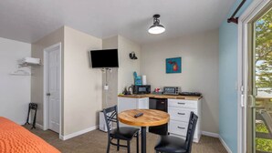 A compact room with a bed, a kitchenette, a TV, and a window with a view. - 2 Cozy Combined Family Studios (Lake City)