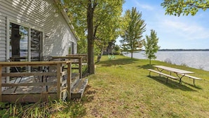 A lakeside cabin with a wooden deck and picnic table. - 2 Cozy Combined Family Studios (Lake City)