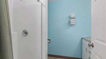 Une salle de bain avec une douche, un porte-serviettes et un lavabo.