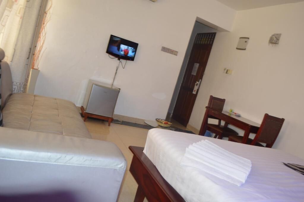 Habitación de hotel con dos camas, televisor montado en la pared, escritorio y una silla.