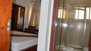 Quarto de hotel com cama, chuveiro e porta de madeira.