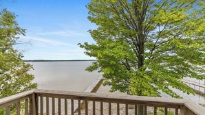 Una terraza de madera con vista a un lago tranquilo y una orilla lejana.