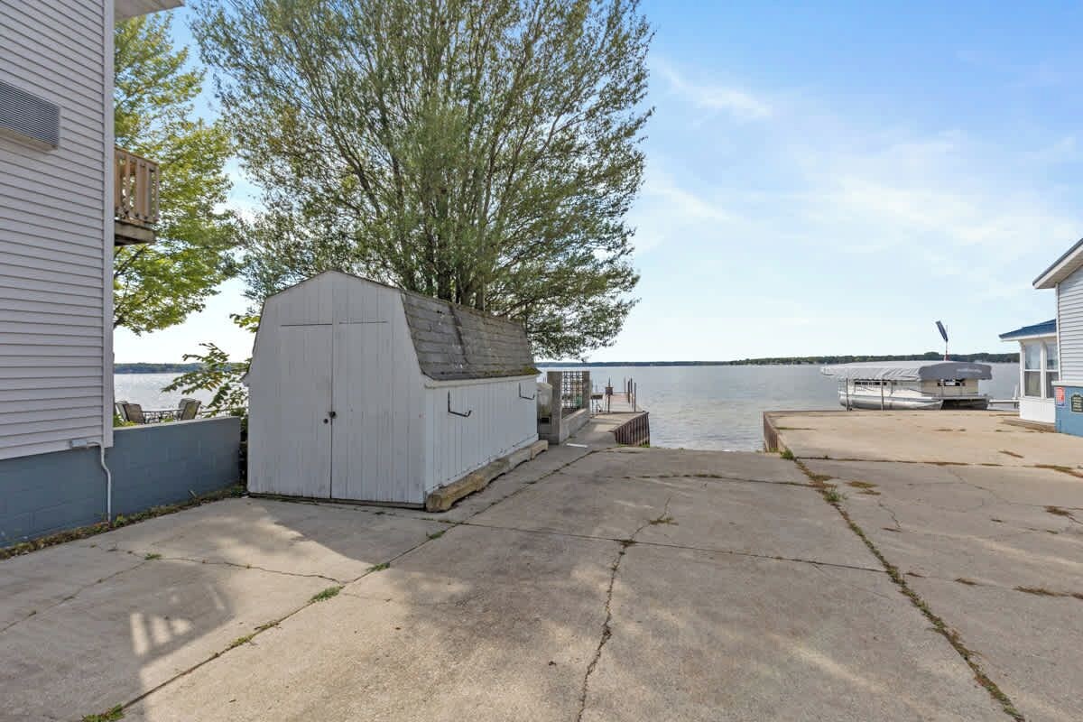 A waterfront property with a dock, a shed, and a boat.
