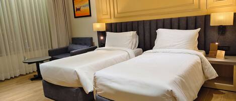 A hotel room with two beds, a small table, a sofa, and a painting on the wall.