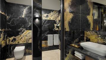 A modern bathroom with a black and gold marble design, a white toilet, and a large sink.