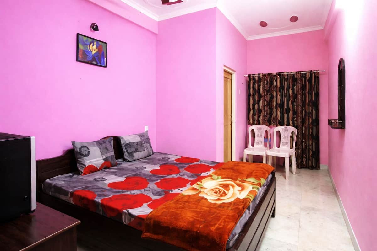 Un dormitorio con cama, televisor, puerta y dos sillas.