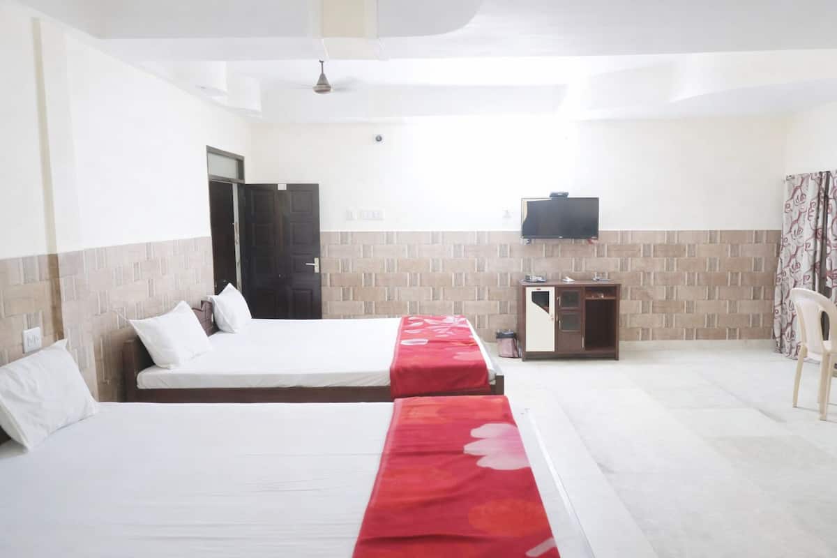 Una habitación de hotel con dos camas, televisión, escritorio y armario.