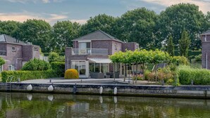 Zona residencial con dos casas de ladrillo, un jardín pequeño y un canal en primer plano.