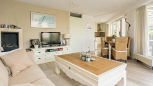 Una sala de estar con sofá, mesa de centro, televisor y un comedor con sillas y una mesa.