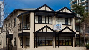 A multi-story building with a balcony, a sign advertising a fully equipped 2-bedroom suite, and a contact number.