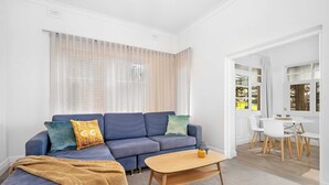 A living room with a sofa, coffee table, and a dining area with chairs and a table.