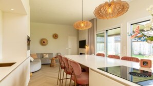 A modern kitchen with a central island, pendant lighting, and a view of the outdoors.