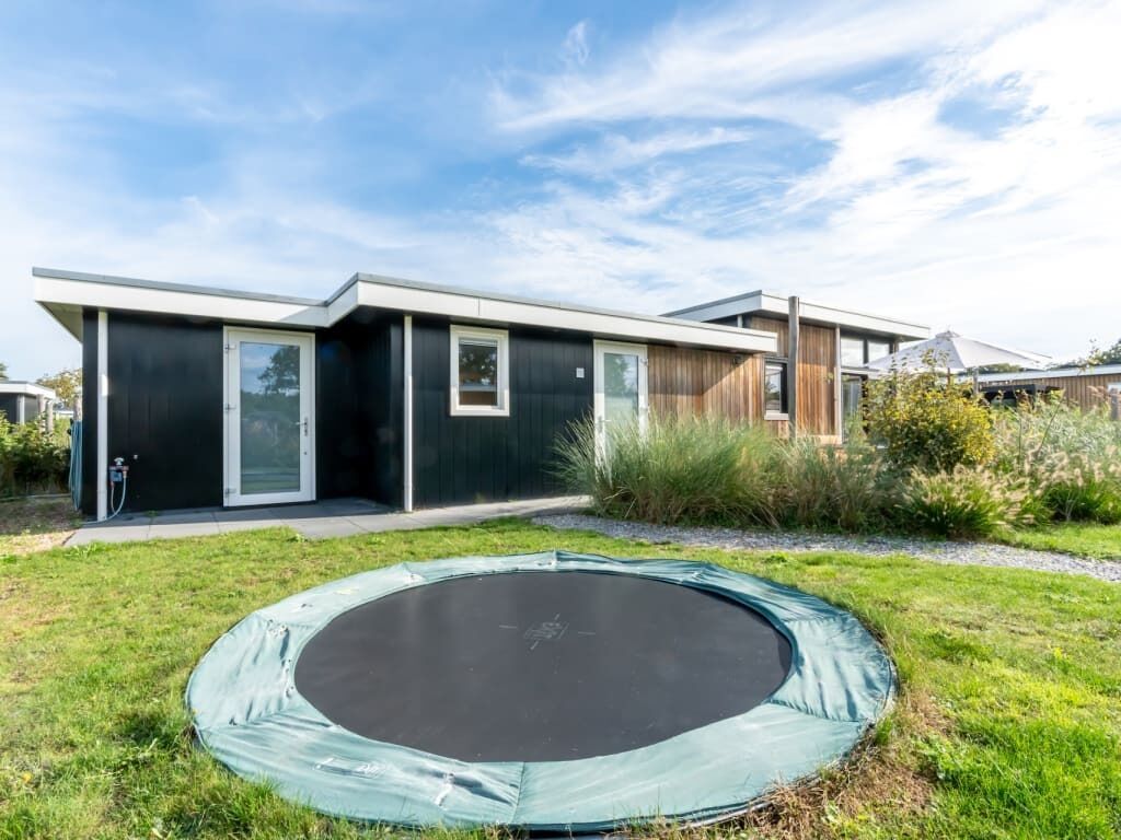 A modern house with a trampoline in the yard.