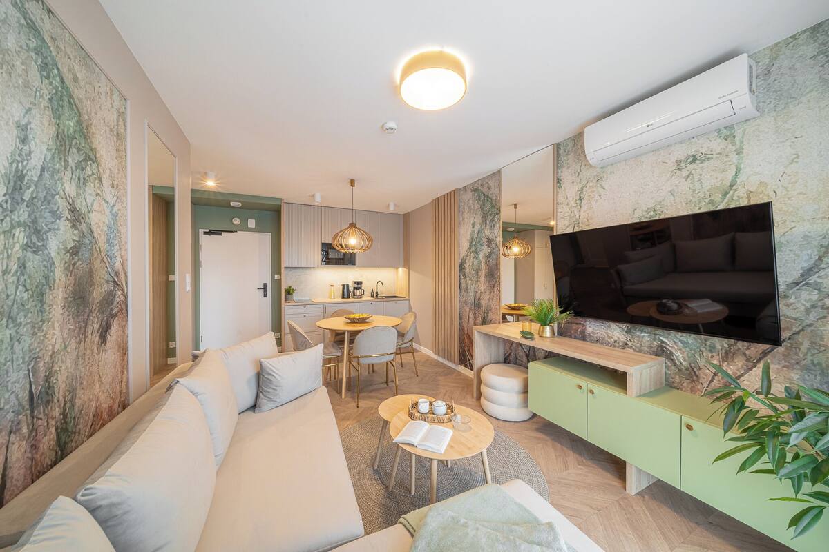 A modern living room with a sofa, coffee table, and a TV mounted on the wall.