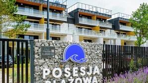 A Posesja Plaza felirattal ellátott tábla, amelyen egy hullámot ábrázoló logó is szerepel, és ez a tábla a tengerparti elhelyezkedésre utal.