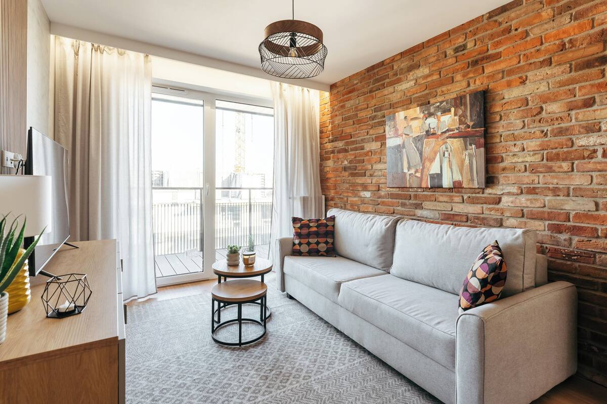 A modern living room with a brick wall, a sofa, a coffee table, and a TV on a wooden stand.