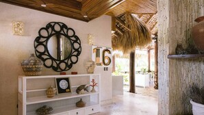 Un pasillo con una consola blanca que exhibe objetos decorativos, un espejo grande y un cartel con el número 16.