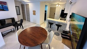 A modern living room with a dining area, a kitchen, and a TV.
