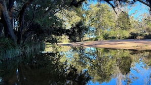 A calm river reflecting trees and a clear sky. - Glamping nature escape at ‘Black Wattle’ 5 minutes from pristine empty beaches (Murrah)