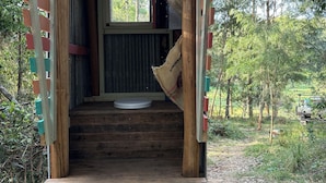 A wooden staircase leading to a covered entrance with a window, surrounded by greenery. - Glamping nature escape at ‘Black Wattle’ 5 minutes from pristine empty beaches (Murrah)