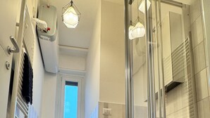 A modern bathroom with a bathtub, a shower, and a glass-enclosed shower area. - Romulus House (Milano)