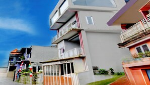 A multi-story building with balconies, a flat roof, and a clear sky. - Hotel O Putra Family Homestay Sikunir (Kejajar)