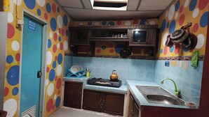 A kitchen with colorful polka dot walls, a blue door, and a sink with a green faucet. - Hotel O Putra Family Homestay Sikunir (Kejajar)