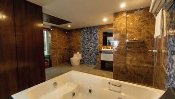 Un baño moderno con una bañera grande, ducha e inodoro.