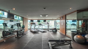A modern gym with cardio machines, a bench press, and a weight bench. - 1BR with Pool 3 Min Walk to Beach  C197 (Patong)