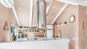Eine moderne Küche mit Holzvertäfelung, einer Edelstahl-Dunstabzugshaube und einer weißen Arbeitsplatte.