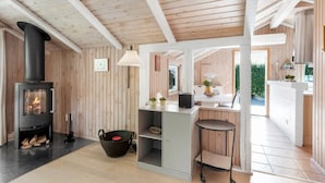 Ein modernes Interieur mit einer holzverkleideten Wand, einem Kamin, einer Küchenzeile und einem Essbereich.