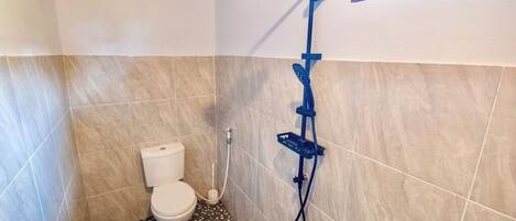 Un baño pequeño con inodoro, ducha y una ventana.