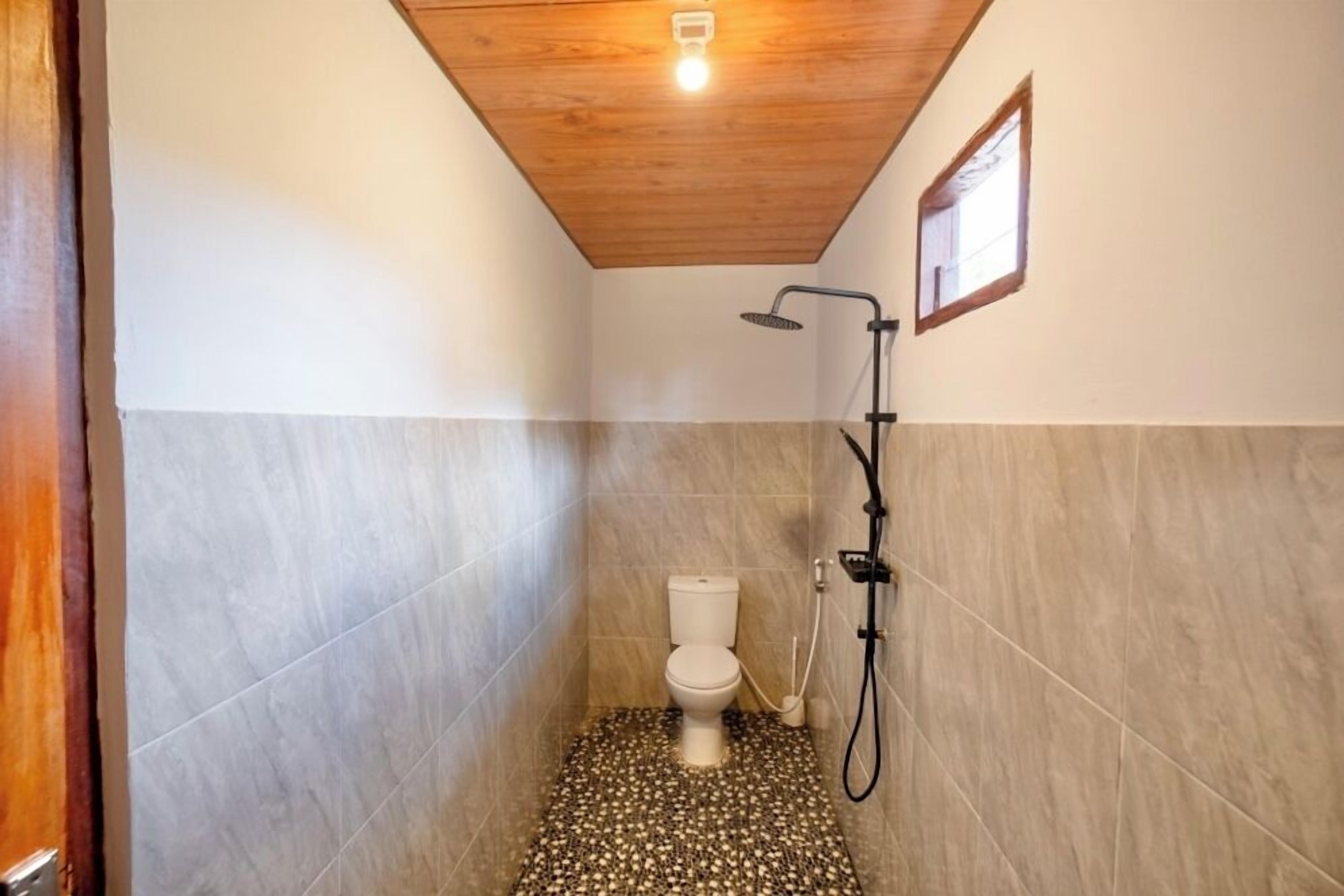 Un baño pequeño y estrecho con inodoro, ducha y techo de madera.