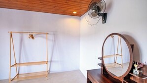 A room with a wooden ceiling, a standing fan, a wooden shelf unit, and a mirror on a wooden dresser. - Royal Escape (Kintamani)