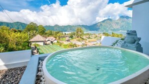 A hot tub with a mountain view, surrounded by greenery and a clear sky. - Royal Escape (Kintamani)