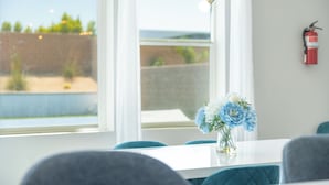 A dining area with a white table, blue chairs, and a vase of flowers. - Pickleball, Pool, Spa, Casita, Firepit, Gameroom (Desert Hot Springs)