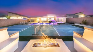 A modern outdoor pool area with a fire feature, lounge chairs, and umbrellas. - Pickleball, Pool, Spa, Casita, Firepit, Gameroom (Desert Hot Springs)