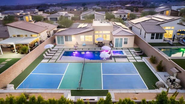 A residential area with a swimming pool, tennis courts, and houses with solar panels. - Pickleball, Pool, Spa, Casita, Firepit, Gameroom (Desert Hot Springs)