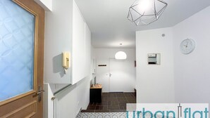 A hallway with patterned flooring, a phone on the wall, a hanging light fixture, and a clock.