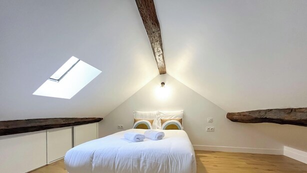 A bedroom with a skylight, a bed with white bedding, and a logo for 'urban flat in paris'.